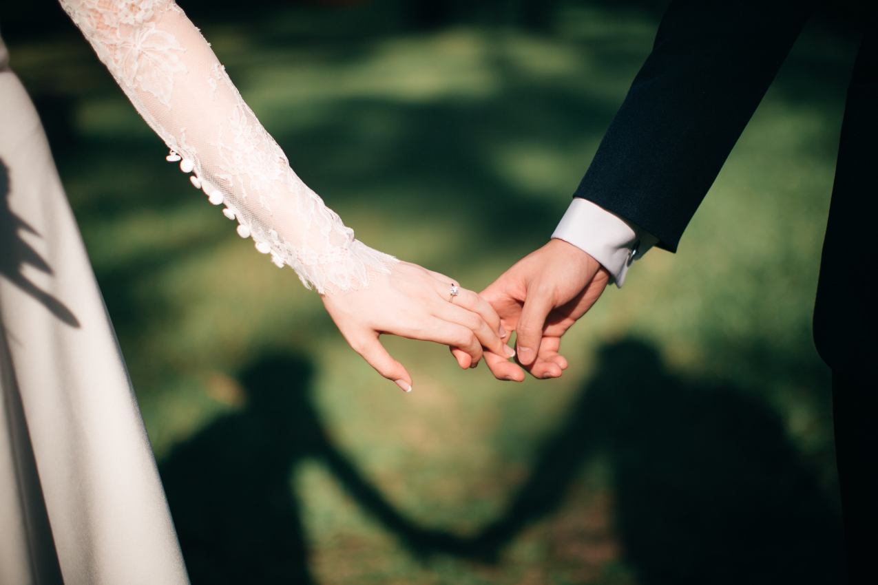 A couple holding hands, symbolizing the rebuilding of trust and love after infidelity, with their shadows forming a heart. Kimberly Brenner, Chicago Marriage Coach, guides couples toward healing and commitment.