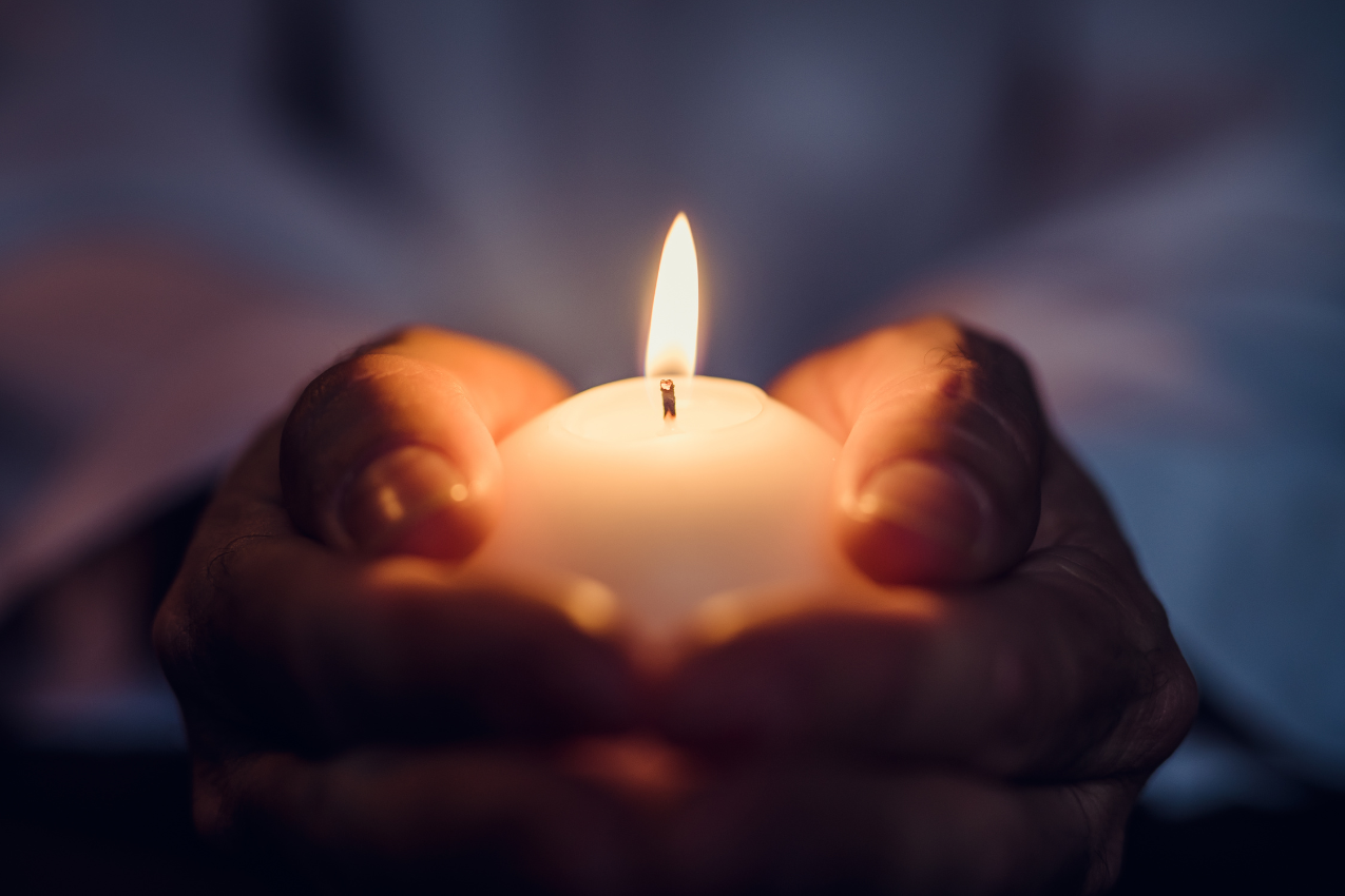 A person gently holding a lit candle, symbolizing hope, healing, and the rekindling of love in a marriage after a second chance.