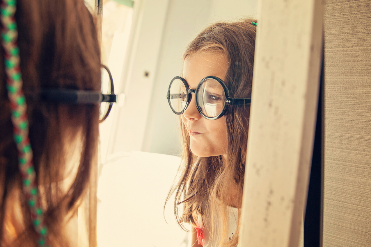 A girl playfully wearing oversized glasses, representing the journey of embracing individuality and self-acceptance. Kimberly Brenner, Chicago Marriage Coach, helps women reclaim their true selves.